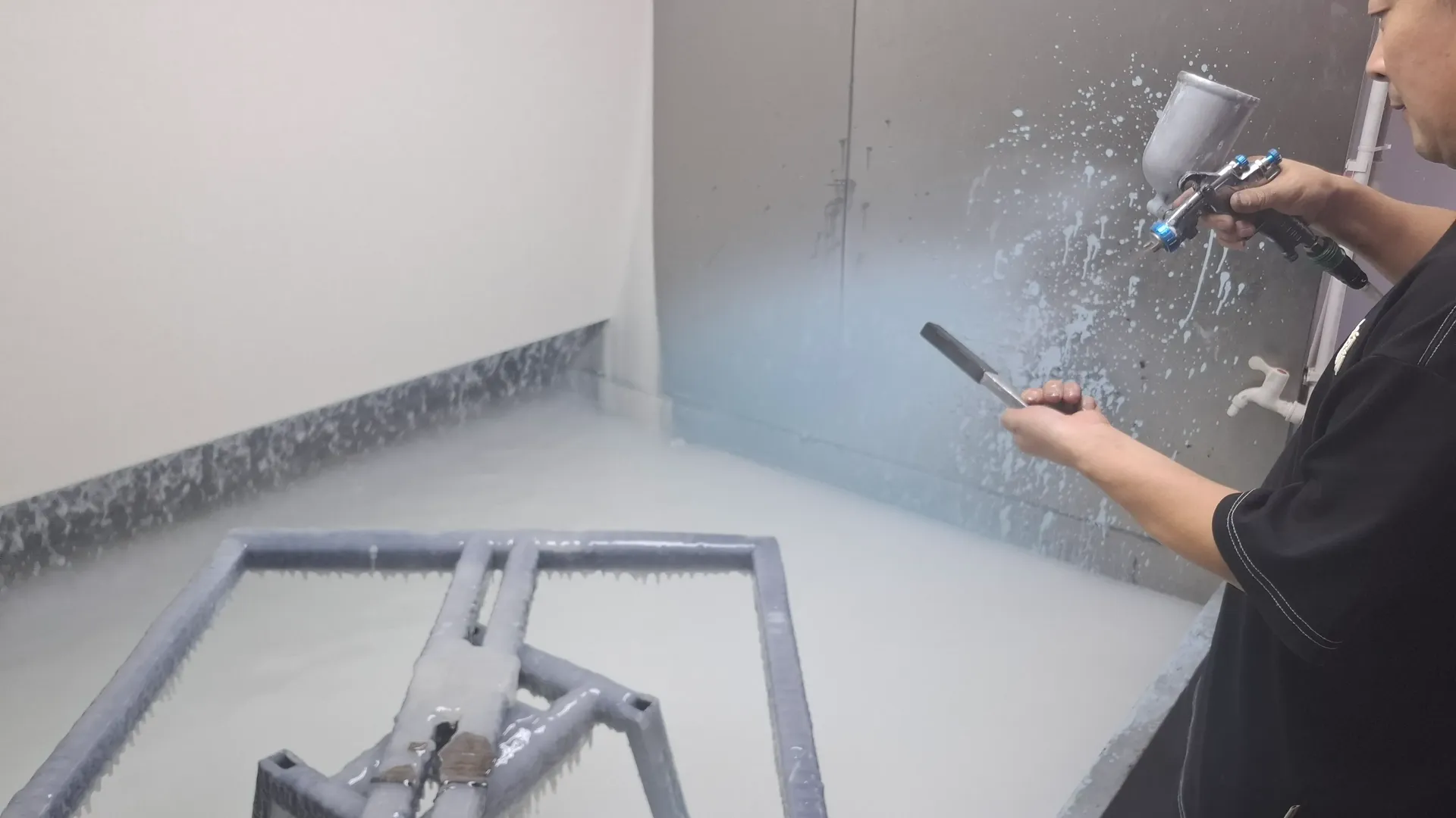 Spray coating a carbon fiber frame inside a water-curtain spray booth